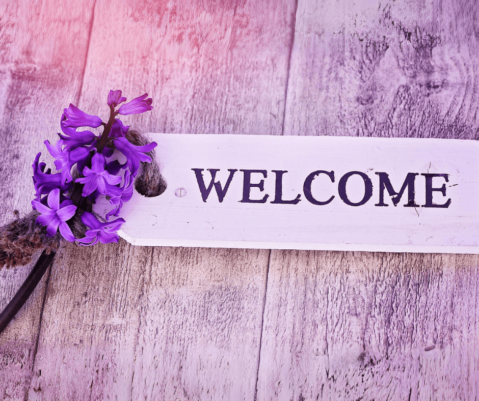 Welcome sign with a wooden background and purple flowers